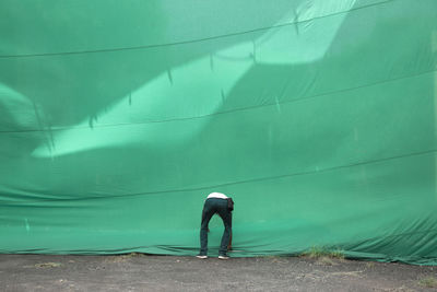 Man adjusting green curtain on road