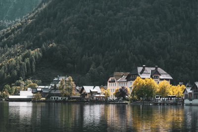 Buildings by lake against trees in forest