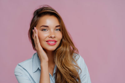 Portrait of smiling young woman against blue background