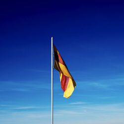 Low angle view of flag against blue sky