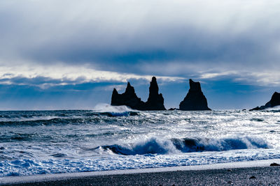 Scenic view of sea with rock formations against cloudy sky