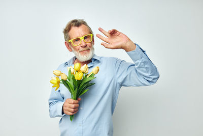 Portrait of young woman holding bouquet against white background