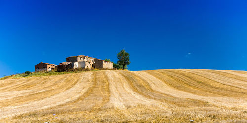 House on field against clear blue sky