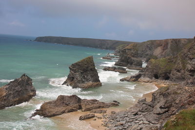 Rocks on shore by sea against sky