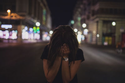 Portrait of woman standing on illuminated street at night