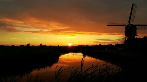 Silhouette of traditional windmill against cloudy sky