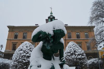 Low angle view of statue against building in winter