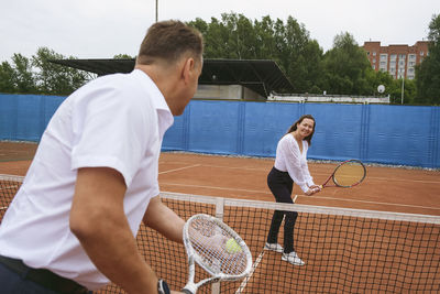 The newlyweds play tennis on the court symbolizing family relations