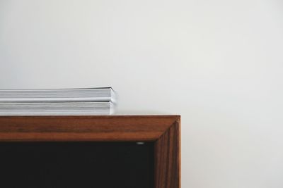 Books on shelf against white wall