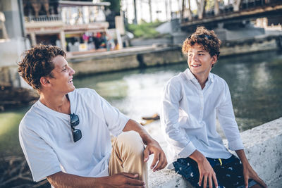 Happy brothers talking and sitting on wall