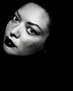 Close-up portrait of young woman against black background