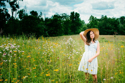 Woman standing by flowering plants on field