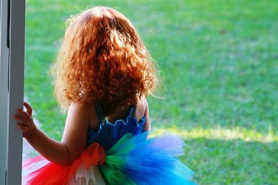 Side view of girl wearing colorful dress on grass