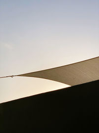 Low angle view of silhouette perching on wall against clear sky