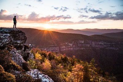 Man standing on mountain against sky during sunset