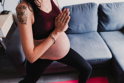 Midsection of pregnant woman exercising at home