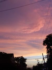 Low angle view of silhouette electricity pylon against sky during sunset