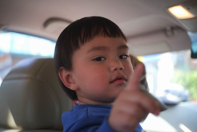Portrait of cute boy gesturing in car