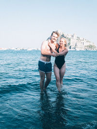 Full length of young woman in swimming pool against sea