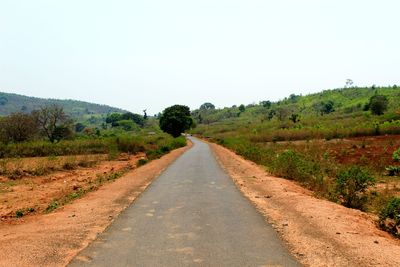 Dirt road along landscape and against clear sky