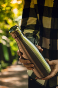 Close-up of unrecognizable female hand holding water bottle. reusable steel thermo water bottle in