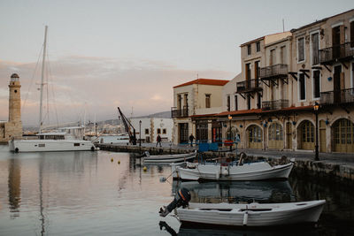 Boats moored at harbor in city against sky