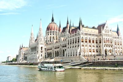 Ferry sailing on river by hungarian parliament building