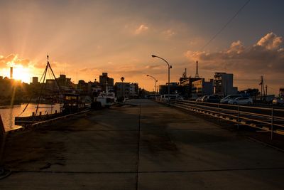 Street by city against sky during sunset