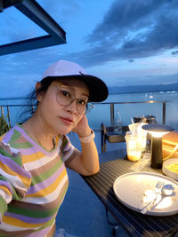 Portrait of young woman sitting with drink on table