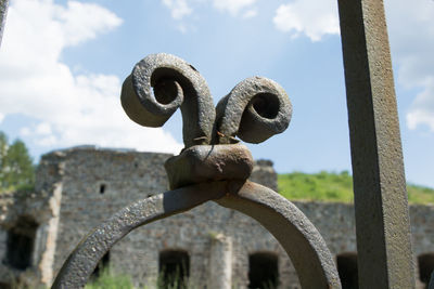 Close-up of metal structure against cloudy sky