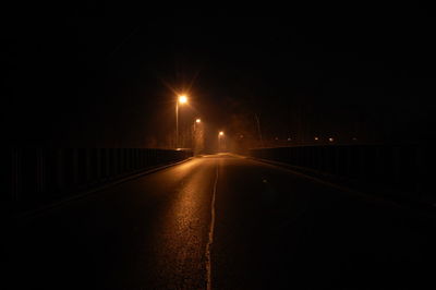 Illuminated road against sky at night