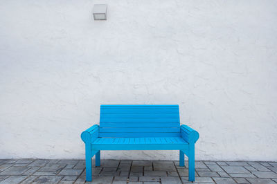 Empty bench against white wall