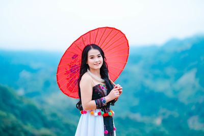 Woman holding red while standing outdoors