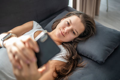 Portrait of young woman lying on bed at home