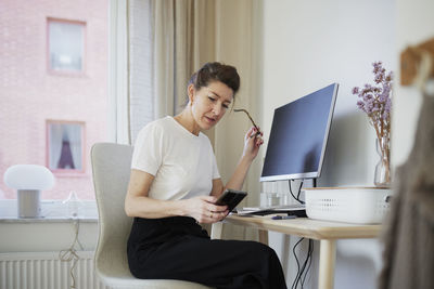 Woman at desk using cell phone