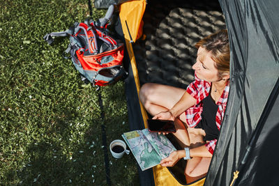 Woman planning next trip while sitting with map in tent. woman relaxing in tent at camping