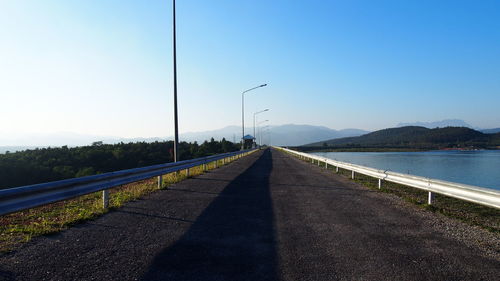 Road leading towards mountain against clear sky