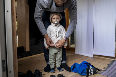 Boy getting dressed by father in mudroom at home