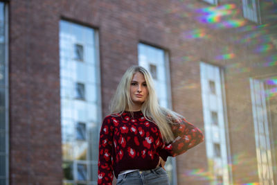 Portrait of young woman standing against buildings