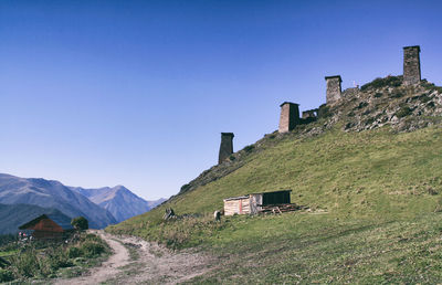 Houses by mountain against clear blue sky