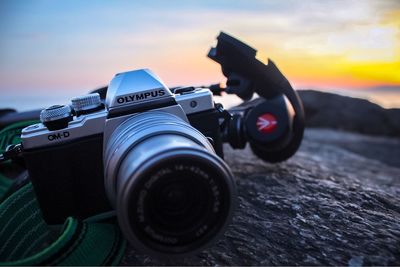 Close-up of camera against sky during sunset