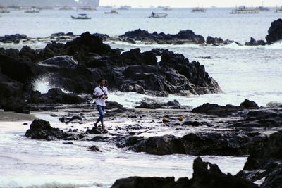 High angle view of man walking on rocks at sea