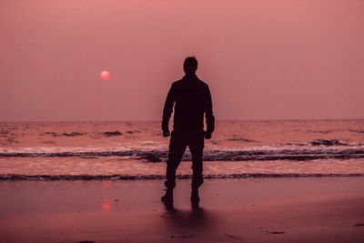 Silhouette man standing at beach against clear sky during sunset