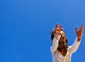 Low angle view of woman against blue sky