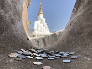 Big buddha image against blue sky view from stone hole with coin merit at wat pha sorn kaew. thai