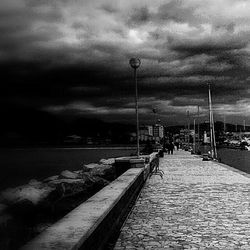 Pier on sea against cloudy sky