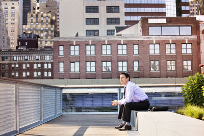 Thoughtful businessman sitting on retaining wall