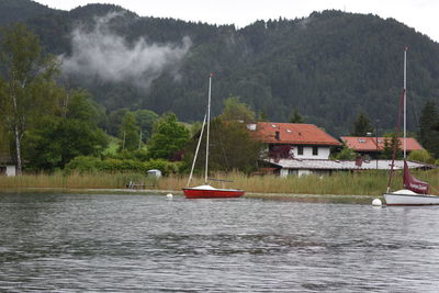 Boats moored in river against mountain