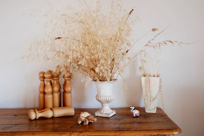 Artificial flowers in vase with wooden toys on table