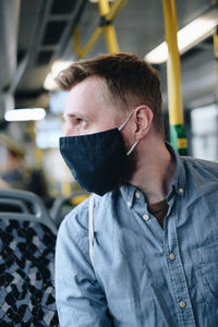 Close-up of mid adult man wearing mask sitting in bus